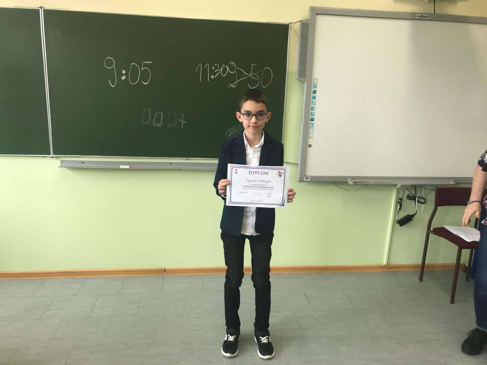 Zdjęcie Szymona, który stoi z dyplomem za zajęcie trzeciego miejsca